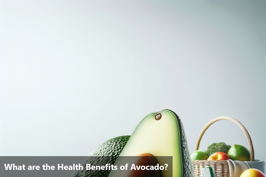 A close-up image of a fresh avocado cut in half with a basket of fruits and vegetables in the background.