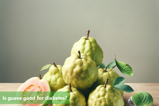 A pile of guava fruits on a wooden table. One guava is cut in half, showing its pink flesh.